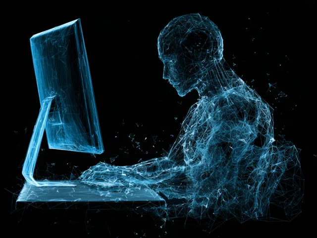 A wireframe figure of blue triangles working at a large computer screen